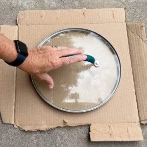 She lays a pot lid over cardboard for this brilliant backyard hack!